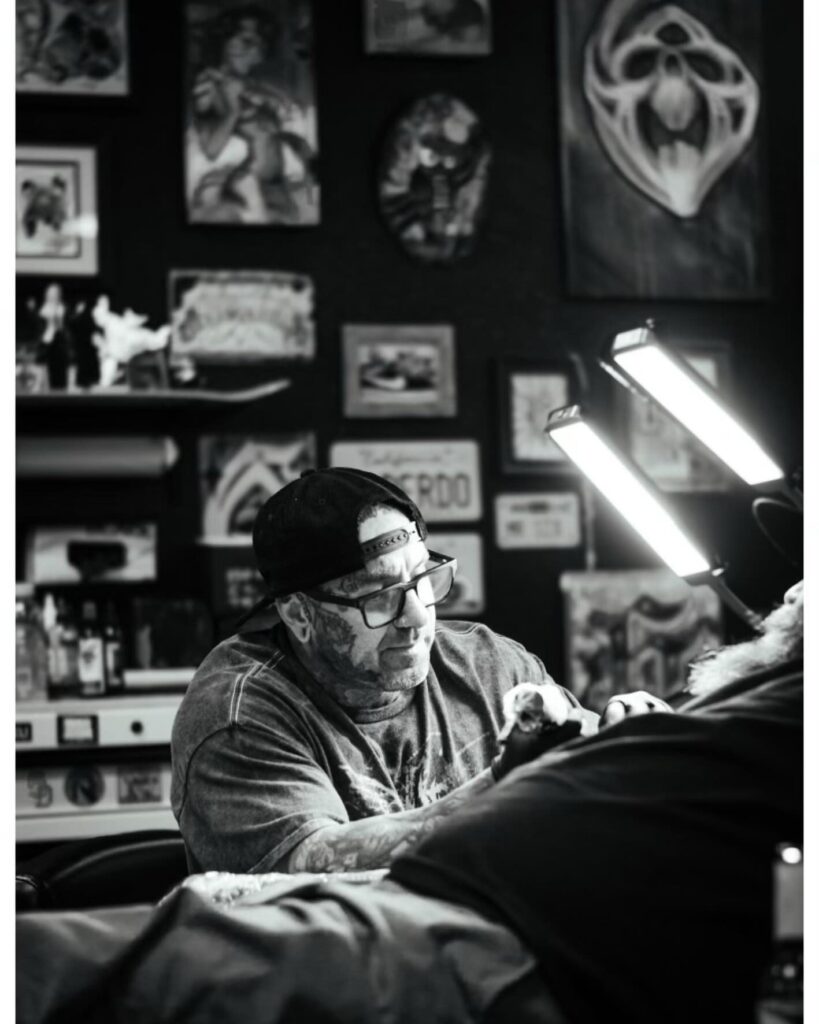 Sixer tattooing a client, black and white portrait